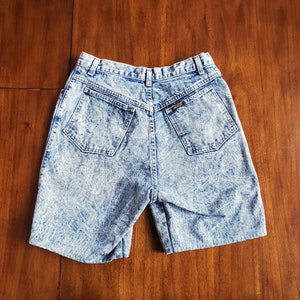 May include: A pair of light blue denim shorts with a faded acid wash finish. The shorts have a high waist and a relaxed fit.