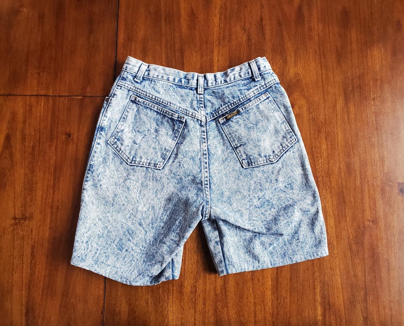 May include: A pair of light blue denim shorts with a faded acid wash finish. The shorts have a high waist and a relaxed fit.