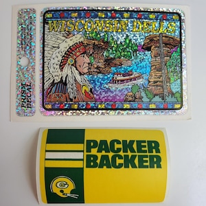 Puede incluir: Una pegatina verde y amarilla con el texto "Packer Backer" y un casco de fútbol verde y blanco con una "G" en él.