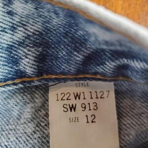 May include: A white tag with black text that reads "Style 122 W1 1127 SW 913 Size 12".