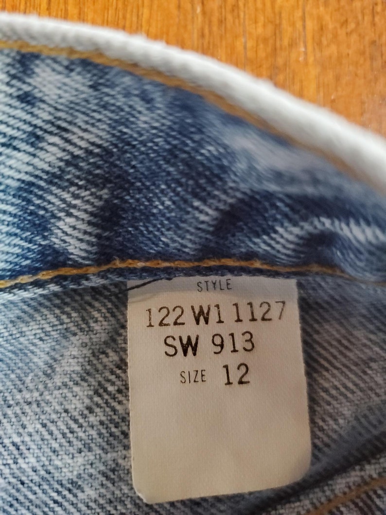 May include: A white tag with black text that reads "Style 122 W1 1127 SW 913 Size 12".