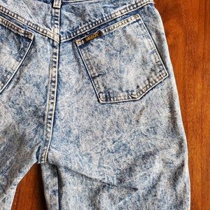 May include: Light blue acid wash denim shorts with a back pocket that has a brown leather label with the text "FRESCO" on it.