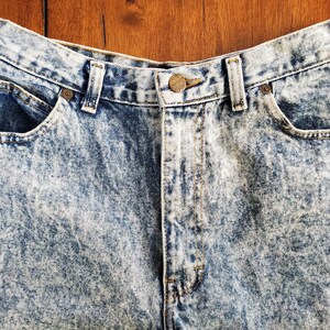 May include: A pair of light blue acid wash denim jeans with a button fly and five pockets.