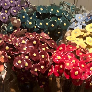 May include: A collection of ceramic flower bouquets in various colors, including purple, teal, yellow, red, orange, pink, and white. Each bouquet features a cluster of small, round flowers with a central yellow dot.