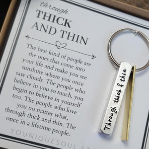 May include: A silver keychain with a small metal tag that reads "Through thick & thin". The keychain is packaged in a white box with a card that reads "Through thick and thin. The best kind of people are the ones that come into your life and make you see sunshine where you once saw clouds. The people who believe in you so much, you begin to believe in yourself too. The people who love you no matter what, through thick and thin. The once in a lifetime people. YOUUNIQUESOUL.ETSY.COM"