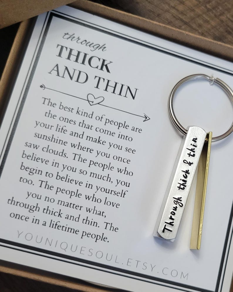 May include: A silver keychain with a small metal tag that reads "Through thick & thin". The keychain is packaged in a white box with a card that reads "Through thick and thin. The best kind of people are the ones that come into your life and make you see sunshine where you once saw clouds. The people who believe in you so much, you begin to believe in yourself too. The people who love you no matter what, through thick and thin. The once in a lifetime people. YOUUNIQUESOUL.ETSY.COM"