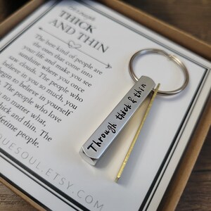 May include: A silver keychain with a quote that reads "Through thick & thin". The keychain is packaged in a white box with a quote that reads "The best kind of people are the ones that come into your life and make you see sunshine where you once saw clouds. The people who believe in you so much, you begin to believe in yourself. The people who love you no matter what, thick and thin. The lifetime people."