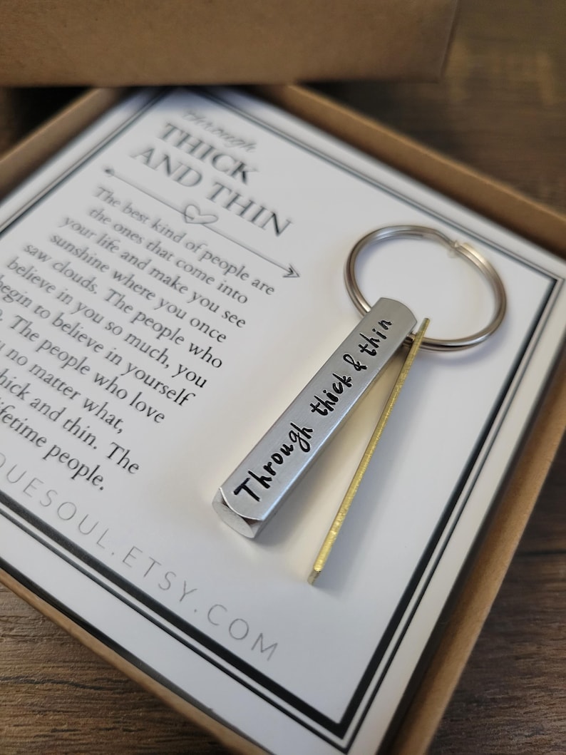 May include: A silver keychain with a quote that reads "Through thick & thin". The keychain is packaged in a white box with a quote that reads "The best kind of people are the ones that come into your life and make you see sunshine where you once saw clouds. The people who believe in you so much, you begin to believe in yourself. The people who love you no matter what, thick and thin. The lifetime people."