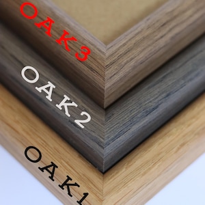 May include: Three wooden picture frames, stacked on top of each other. The top frame is a dark brown wood, the middle frame is a gray wood, and the bottom frame is a light brown wood. Each frame has the word "OAK" and a number, 1, 2, or 3, printed on the side.