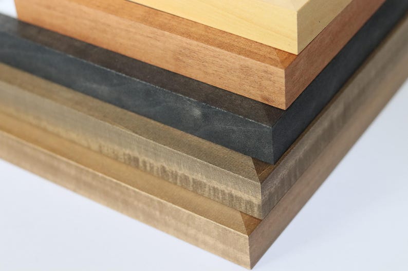 May include: A stack of five wooden picture frames in various shades of brown, from light to dark.