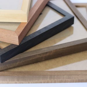 May include: Four different wooden picture frames stacked on top of each other. The frames are in various shades of brown, black, and natural wood.