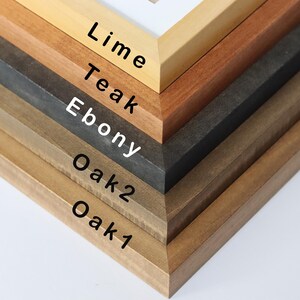 May include: Close-up of six different wood picture frames stacked on top of each other. The frames are labeled from bottom to top: Oak 1, Oak 2, Ebony, Teak, Lime.