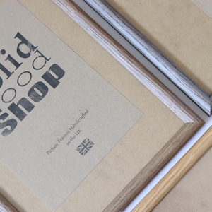 Puede incluir: Tres marcos de fotos hechos de madera maciza. Los marcos son de diferentes colores y estilos. Los marcos est&aacute;n etiquetados como "Solid Wood Shop" y "Marcos de fotos hechos a mano en el Reino Unido".