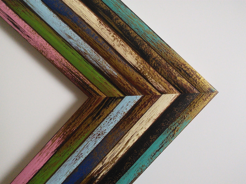May include: A corner of a colorful wooden frame with a chevron pattern. The frame is made of reclaimed wood and has a distressed finish. The colors are pink, blue, green, brown, and gold.