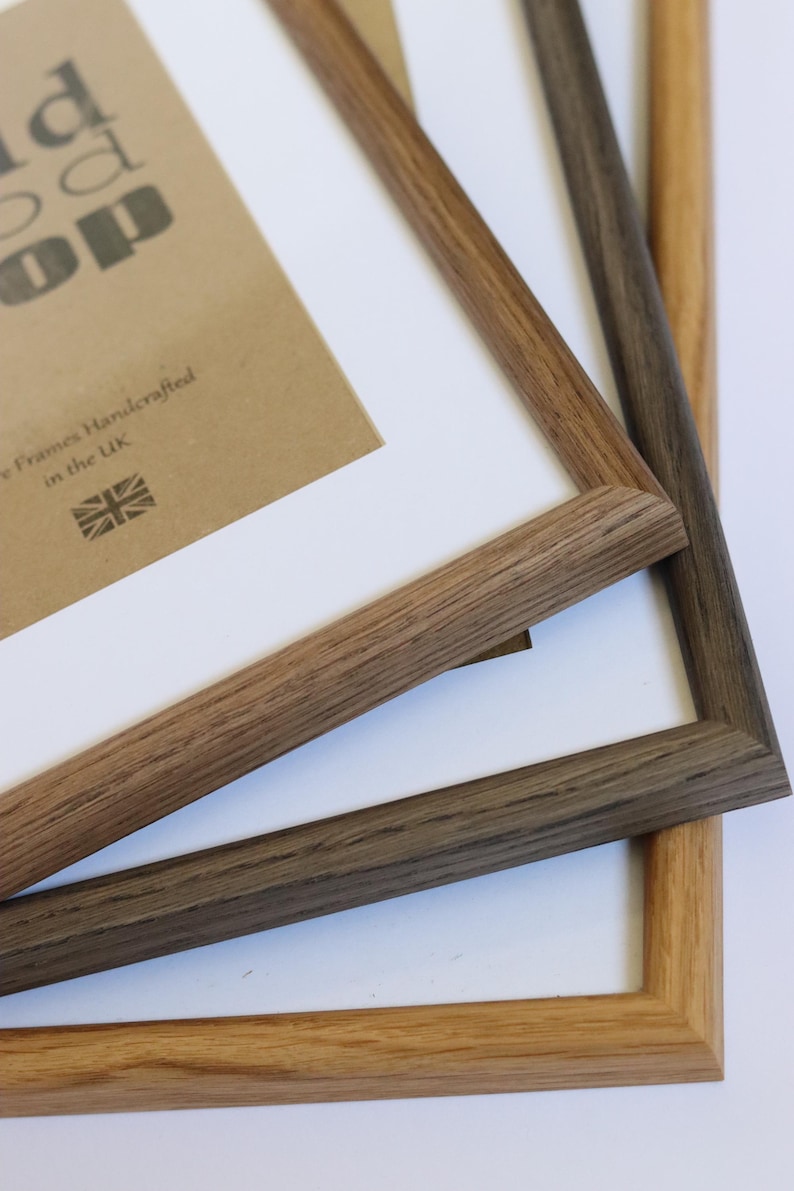 Puede incluir: Tres marcos de fotos de madera apilados uno encima del otro. El marco superior es de madera marr&oacute;n claro, el marco del medio es de madera marr&oacute;n oscuro y el marco inferior es de color madera natural. Los marcos son todos del mismo tama&ntilde;o y tienen un dise&ntilde;o simple y cl&aacute;sico.
