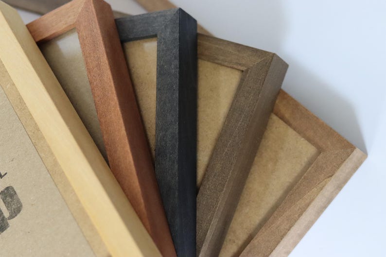 May include: Four different picture frames made of wood. The frames are in various shades of brown, black, and natural wood. The frames are all different sizes and have a simple design.