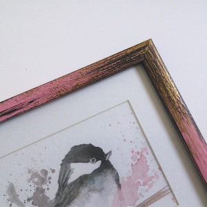 May include: A framed watercolor painting of a bird with pink and gold accents on the frame.