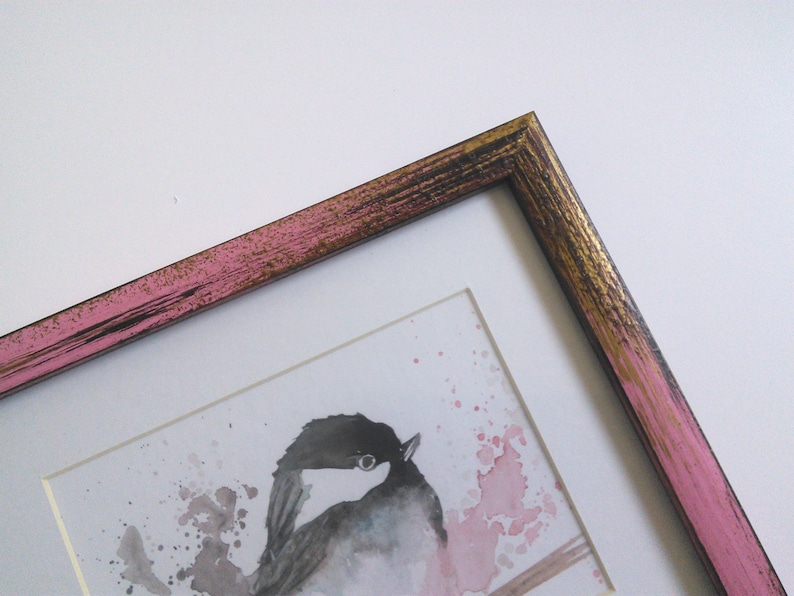 May include: A framed watercolor painting of a bird with pink and gold accents on the frame.