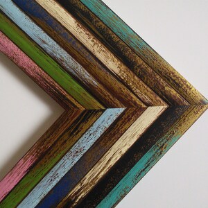 May include: A corner of a colorful wooden frame with a chevron pattern. The frame is made of reclaimed wood and has a distressed finish. The colors are pink, blue, green, brown, and gold.