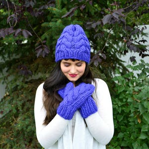 May include: A matching set of knitted winter accessories in a vibrant blue hue. The set includes a cable-knit beanie and a pair of mittens. The beanie features a textured pattern, and the mittens have a similar design. The accessories are made of a soft, warm material.