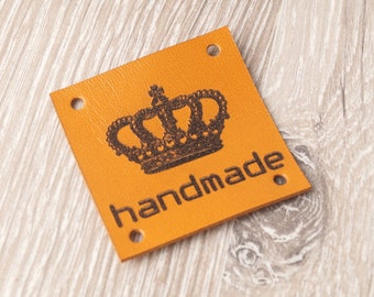 May include: Orange leather tag with a black crown and the word "handmade" printed on it.