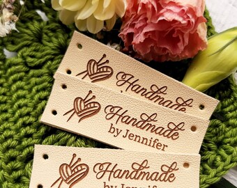 May include: Three beige leather tags with holes for stitching. Each tag has a brown engraved design of a heart with knitting needles and the text "Handmade by Jennifer".