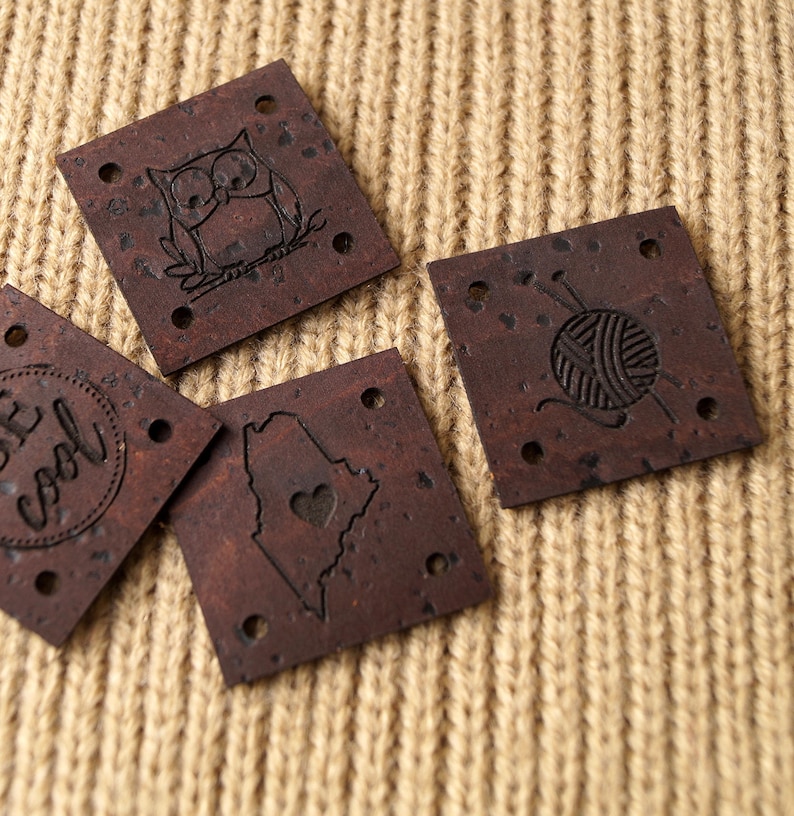 May include: Four brown cork fabric patches with different designs. The designs include an owl, a yarn ball with knitting needles, a state outline with a heart, and a circle with the text "Be Cool".