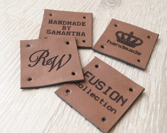 May include: Four square brown leather tags with black text. One tag reads "HANDMADE BY SAMANTHA", another has a crown above the word "handmade", a third displays the letters "R&W", and the last says "FUSION collection". Each tag has four holes.
