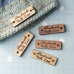 May include: Five wooden tags with the text "Handmade with Love" engraved on them. The tags are on a blue and white polka dot background.