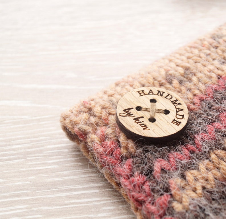 May include: Close-up of a knitted hat with a brown, pink, and gray color scheme. A wooden button with the text "HANDMADE by kim" is attached to the hat.