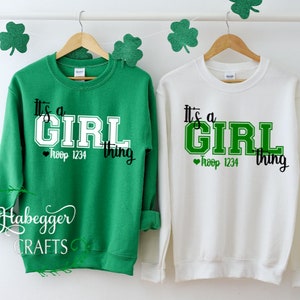 May include: Two green and white sweatshirts with the text "It's a Girl thing" and a heart with "Troop 1234" printed on them.