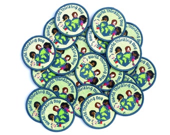 May include: A pile of round, green and blue embroidered patches with the text "World Thinking Day" and a graphic of children holding a globe.