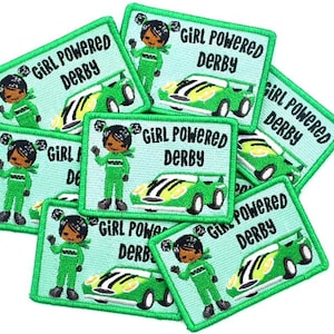 May include: A stack of green and black iron-on patches with the text "Girl Powered Derby" and a cartoon image of a girl in a racing suit driving a green race car.