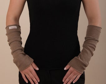 May include: A woman wearing a black tank top and brown fingerless gloves. The gloves have a small label that says "smoothskin".