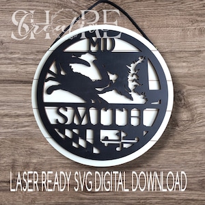 May include: A white and black round wooden sign with a crab, the state of Maryland, and the text "MD SMITH" on it. The sign has a black and white checkered pattern around the edge.