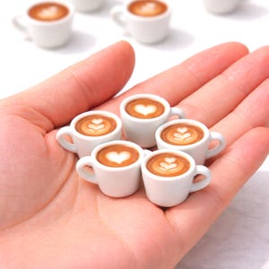 Op de afbeelding: Een set van drie keramische mokken met een gespikkelde, matte afwerking. De mokken zijn in crème, lichtgrijs en donkergrijs. Elke mok heeft een eenvoudig, minimalistisch ontwerp, perfect voor koffie of thee.