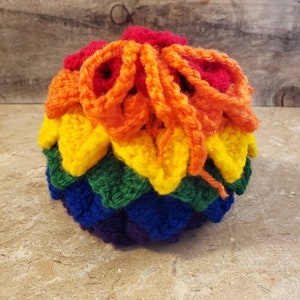 Könnte beinhalten: Eine regenbogenfarbene gehäkelte Kordeltasche mit einem gerüschten Oberteil. Die Tasche ist in den Farben des Regenbogens gefertigt, mit Rot, Orange, Gelb, Grün, Blau und Lila.