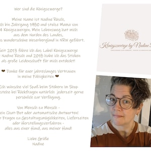 May include: A white informational card featuring German text about the brand K&ouml;nigszwerge by Nadine R&ouml;sch, including a logo with a floral illustration and a photograph of a person with short dark hair wearing round glasses and a brown and white shirt.