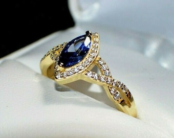 May include: A gold ring with a marquise-shaped blue sapphire surrounded by a halo of smaller diamonds. The band is twisted and features additional diamonds.