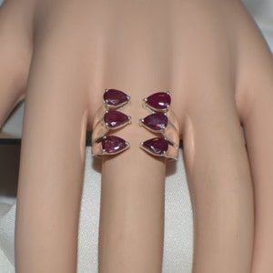 May include: A silver ring with six pear-shaped ruby gemstones set in a three-row design.