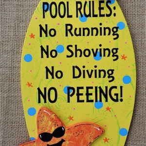 May include: Yellow oval wooden sign with a starfish wearing sunglasses. The sign reads "POOL RULES: No Running No Shoving No Diving NO PEEING!"