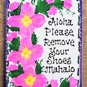 May include: A white wooden sign with a purple border and pink flowers painted around the edges. The sign says "Aloha Please Remove Your Shoes Mahalo".