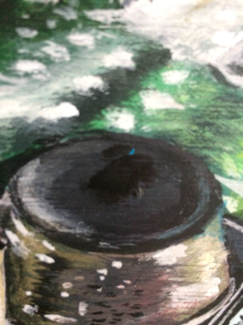 May include: A close-up of a black and silver painted metal lid with a blue dot in the center. The lid is surrounded by a green and white abstract background.