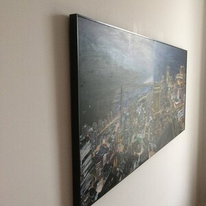 May include: A framed canvas print of a city skyline at night. The city is lit up with lights and the sky is dark with clouds. The print is in a black frame.