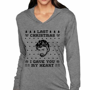 Op de afbeelding: Grijs hoodie met lange mouwen met een zwart-wit kerstthema met een mannengezicht en de tekst "Last Christmas I Gave You My Heart."