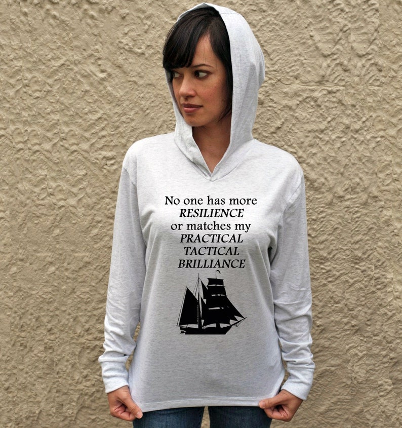 Puede incluir: Una sudadera gris de manga larga con capucha con un gr&aacute;fico de velero negro y el texto "No one has more RESILIENCE or matches my PRACTICAL TACTICAL BRILLIANCE".