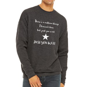 K&ouml;nnte beinhalten: Ein dunkelgrauer Sweatshirt mit einem wei&szlig;en Stern und dem Text "There's a million things I haven't done but just you wait JUST YOU WAIT".
