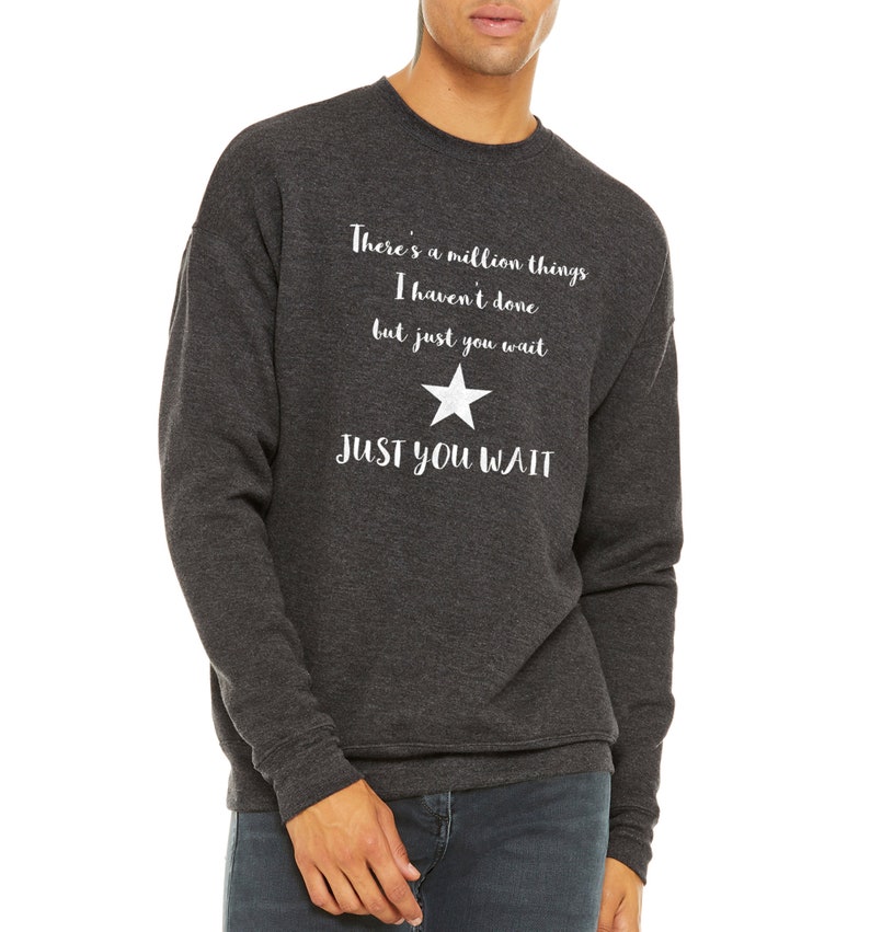 K&ouml;nnte beinhalten: Ein dunkelgrauer Sweatshirt mit einem wei&szlig;en Stern und dem Text "There's a million things I haven't done but just you wait JUST YOU WAIT".