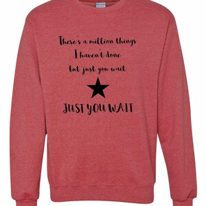 K&ouml;nnte beinhalten: Roter Melange-Sweatshirt mit schwarzem Text, der "There's a million things I haven't done but just you wait JUST YOU WAIT" lautet, und einem schwarzen Stern.