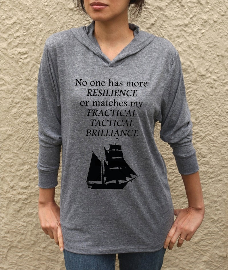 Puede incluir: Camiseta gris de manga larga con capucha con el texto "No one has more RESILIENCE or matches my PRACTICAL TACTICAL BRILLIANCE" y una silueta de un velero.